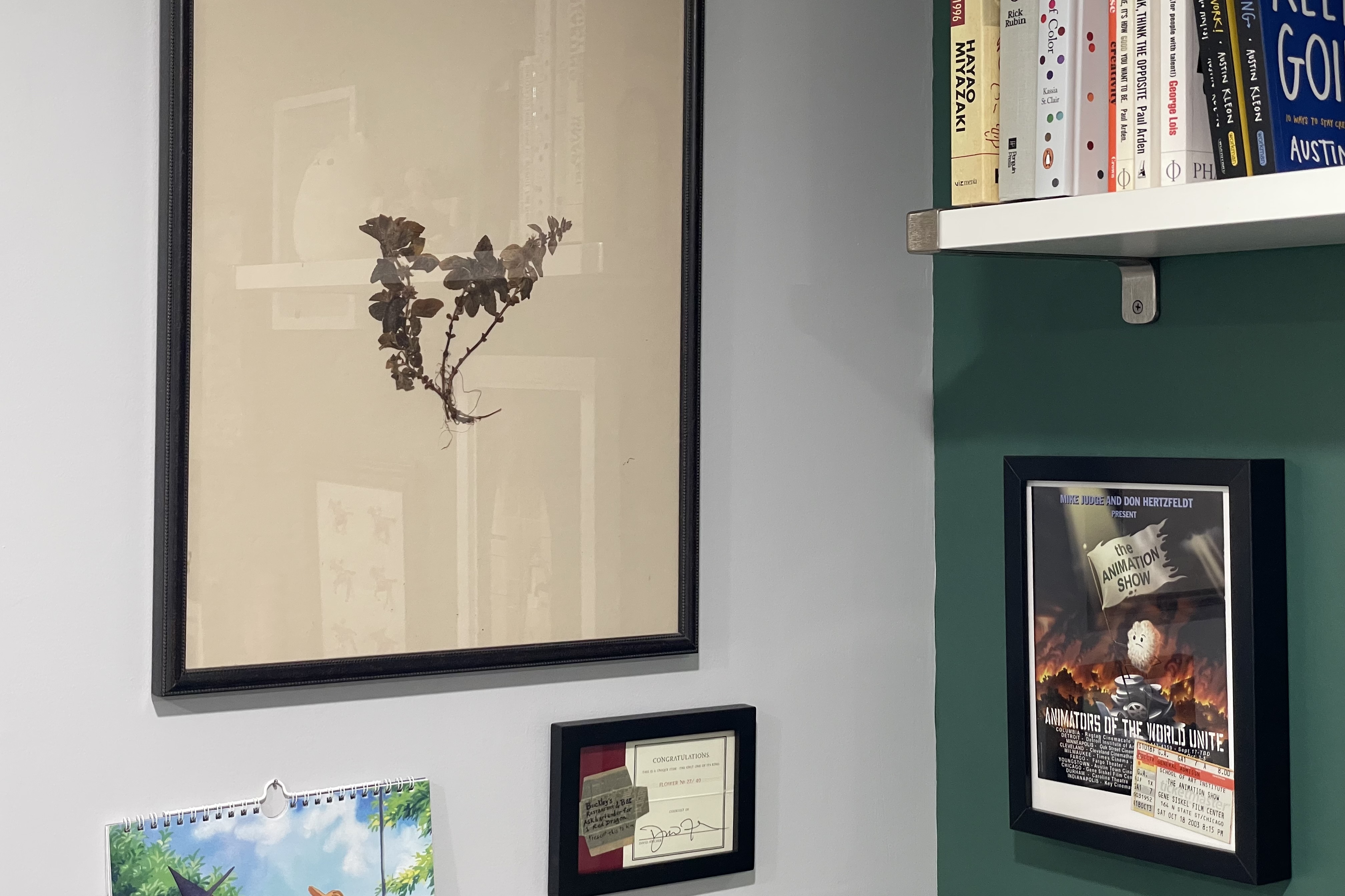 Corner wall with framed pressed flower, signed note from David Fincher, and framed program and ticket stub from The Animation Show