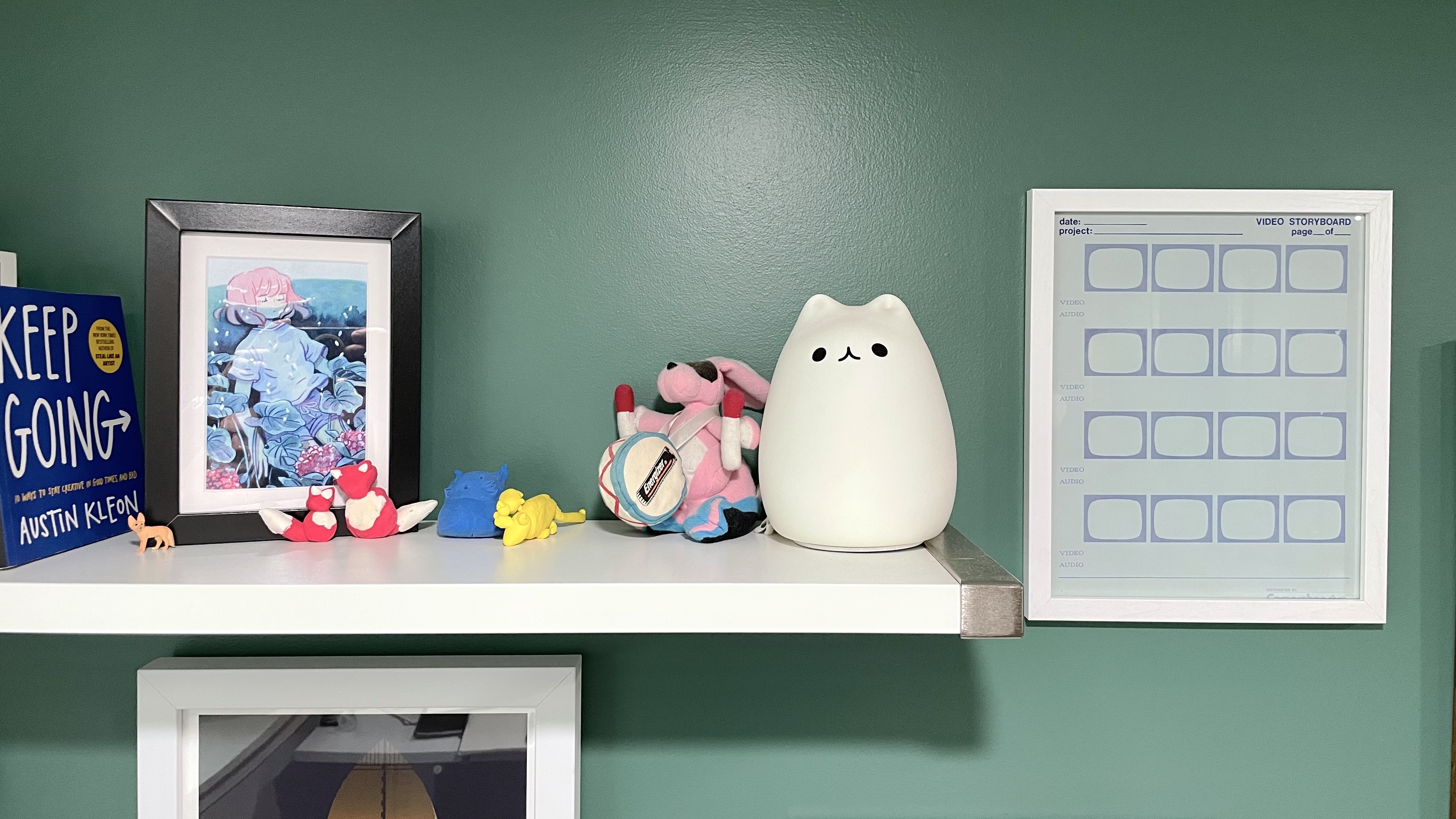 Shelf with some odds and ends including a glowcat and watercolor print with a framed template for storyboarding to the right